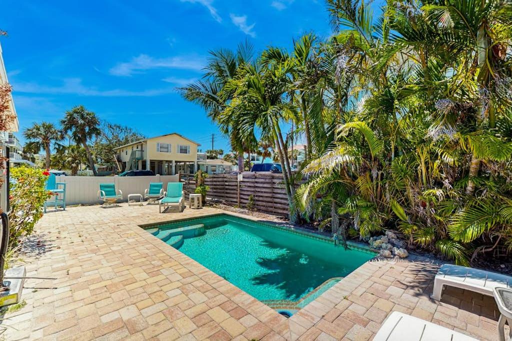 a swimming pool in a yard with palm trees at Gertie's Coconut House in Holmes Beach