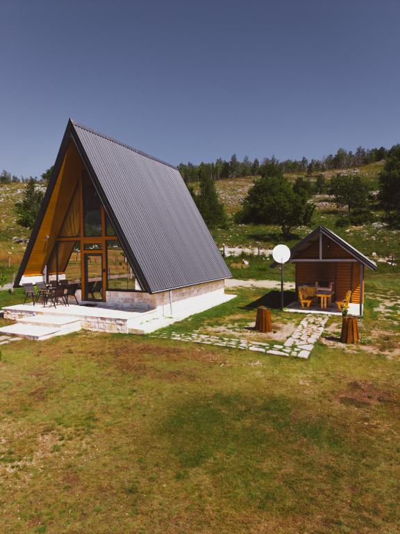 a large wooden house with a table in a field at Sunrise House in Plužine