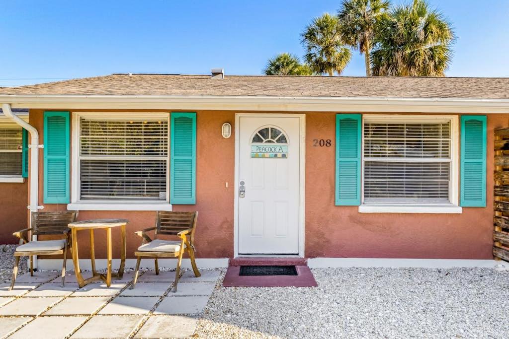 a house with two chairs and a white door at Holmes Beach Bungalow - A in Holmes Beach