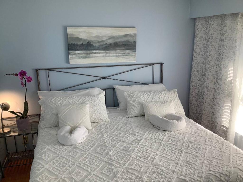 a bedroom with a white bed with white pillows at Cozy nest in Coquitlam