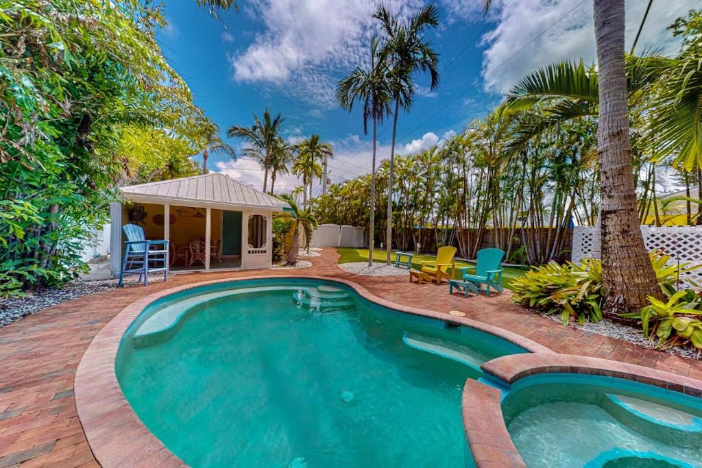 a swimming pool in a backyard with palm trees at The Wee Cottage in Anna Maria
