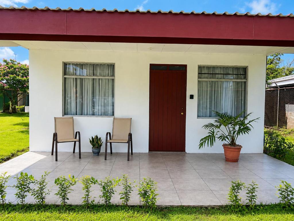a house with two chairs and a red door at Arenal Rental CASA PALMERA UNO in Arenal
