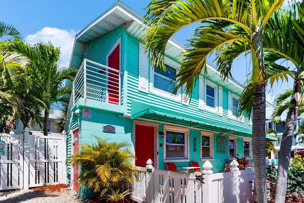 a colorful house with a white fence and palm trees at Nautical Nook at Bayview Inn in Bradenton Beach