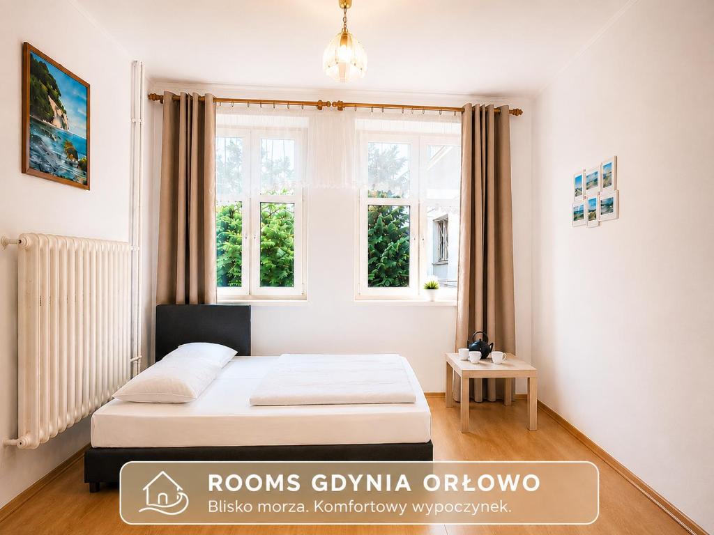 a bedroom with a bed and two windows at Rooms Gdynia Orłowo in Gdynia