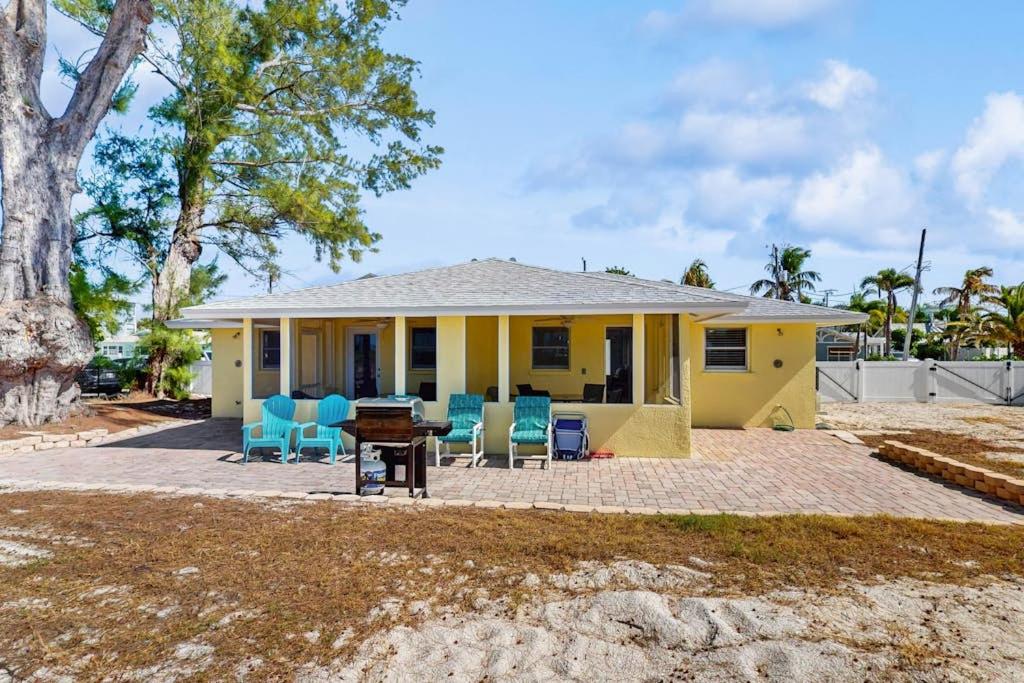 a yellow house with blue chairs and a table at Playa Casanas South in Holmes Beach