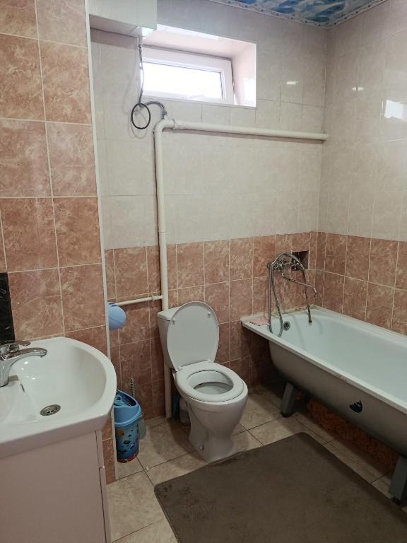 a bathroom with a toilet and a tub and a sink at BoNa Guest in Bishkek