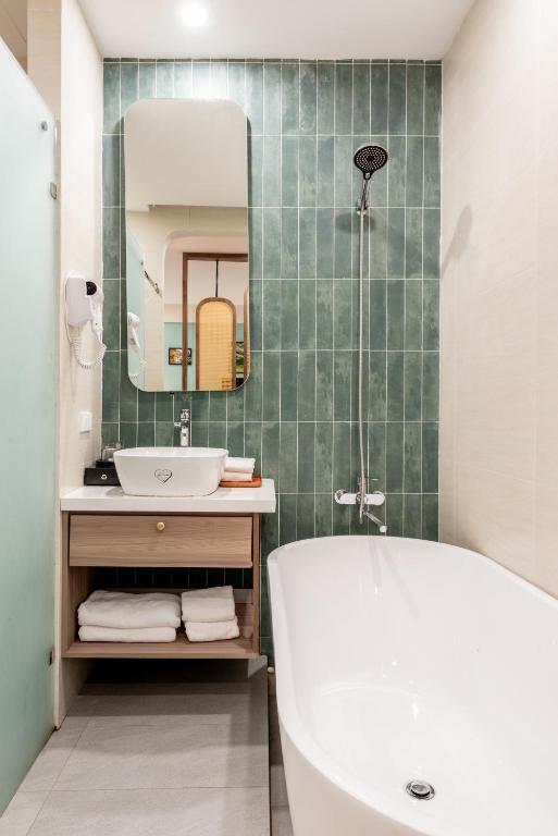 a bathroom with a tub and a sink and a mirror at La May Boutique hotel in Ninh Binh