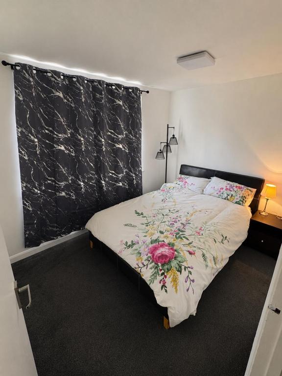 a bedroom with a bed with a floral blanket on it at Beautiful Double room in Peterborough