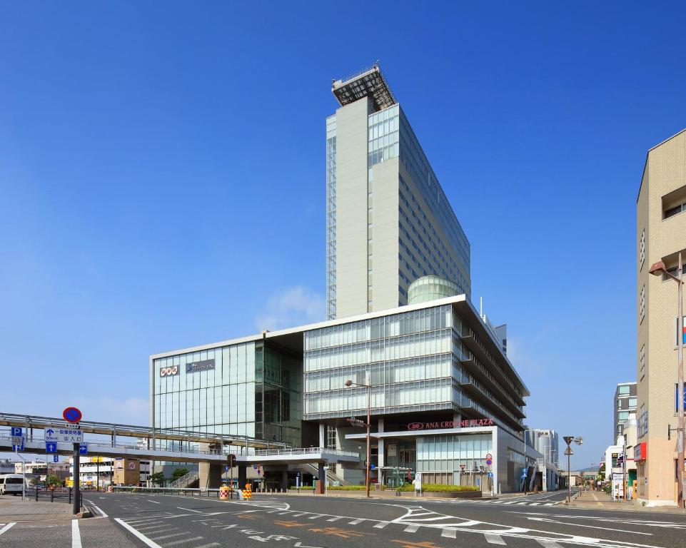 a tall glass building in a city with a street at ANA Crowne Plaza Okayama by IHG in Okayama