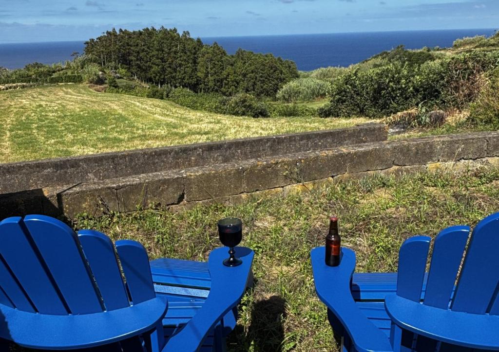 two blue chairs and a table with a bottle of beer at Casa das Brisas Matinais in Conceição