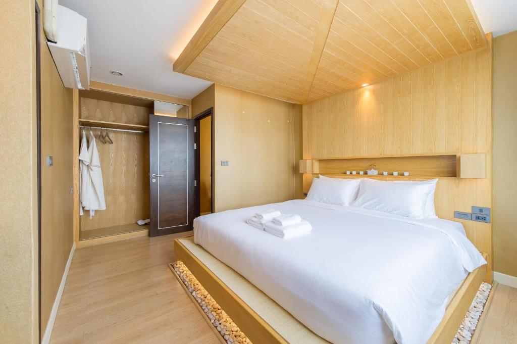 a bedroom with a large white bed and a closet at Zenniq in Bangkok