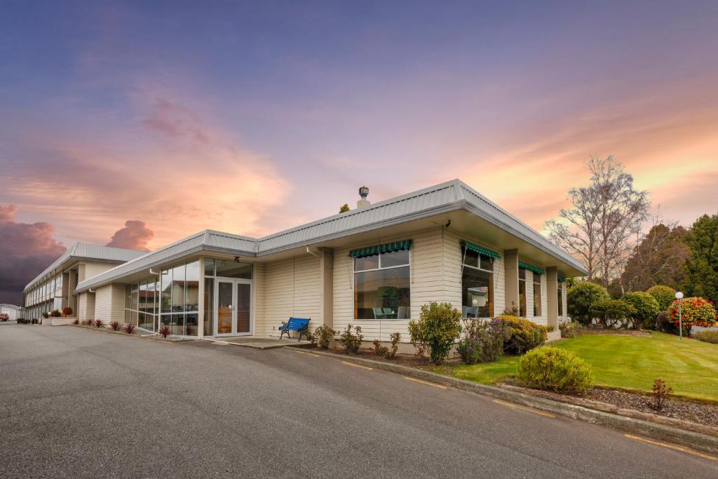 a house on a street with a sunset at Kingsgate Hotel Te Anau in Te Anau