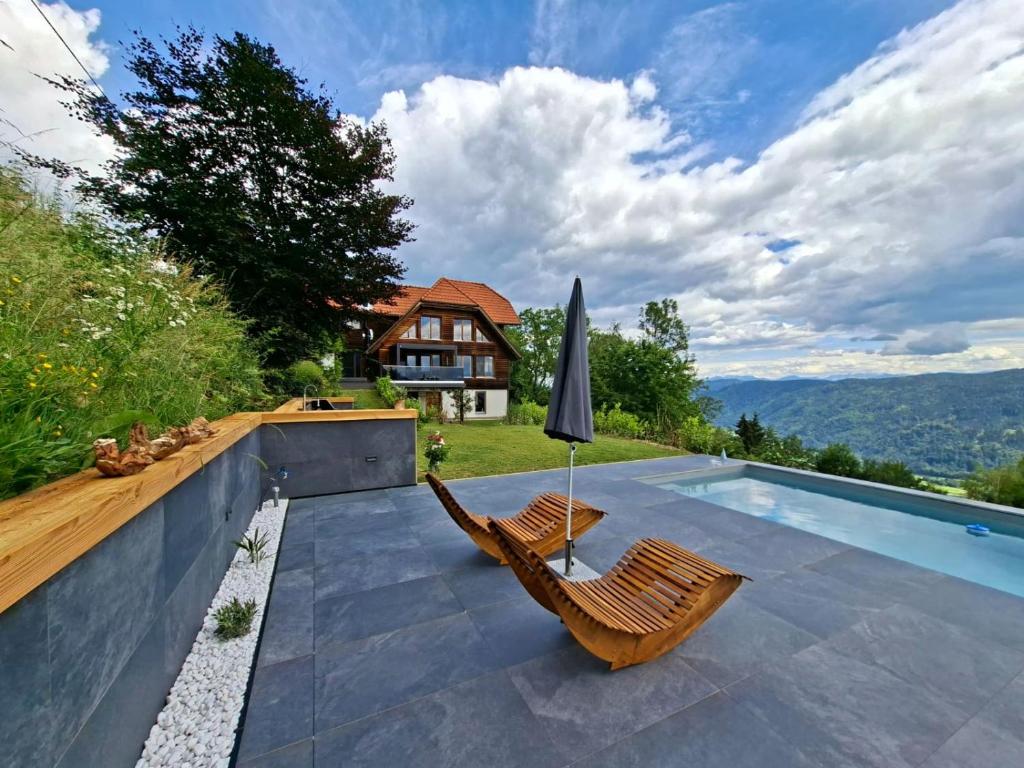 a swimming pool with two chairs and an umbrella at Bergidylle Winkler in Steindorf am Ossiacher See