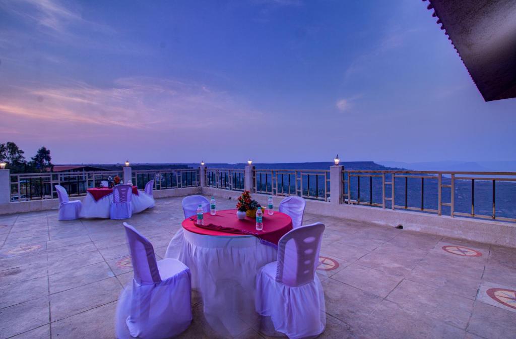 a patio with a table and chairs on a balcony at TAJ VILLA Mahabaleshwar in Mahabaleshwar