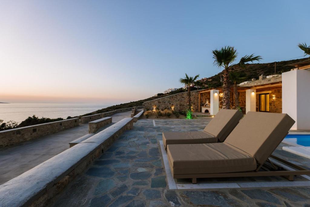 a patio with two lounge chairs and the ocean at Naxos Royal Villas in Stelida