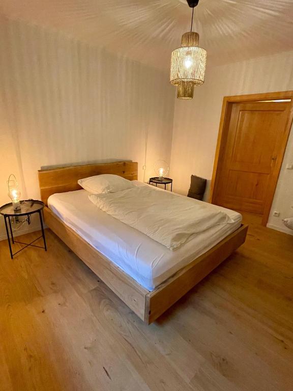 a bedroom with a bed and two tables and a chandelier at Kaiserblick Lodge Oberaudorf in Oberaudorf