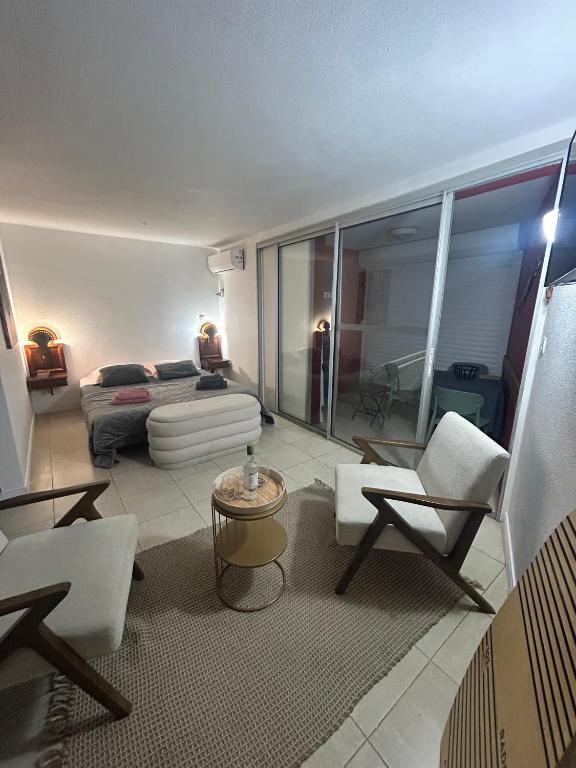 a living room with white chairs and a couch at studio Sainte Anne 2mn a pieds de la plage in Sainte-Anne