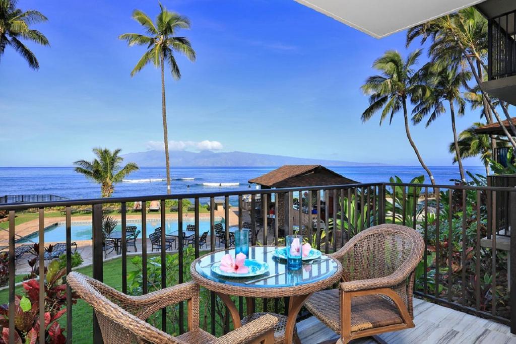 a table and chairs on a balcony overlooking the ocean at Noelani 113 in Kahana