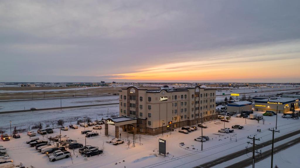 a building in a parking lot with cars in the snow at Radisson Hotel Edmonton Airport in Leduc