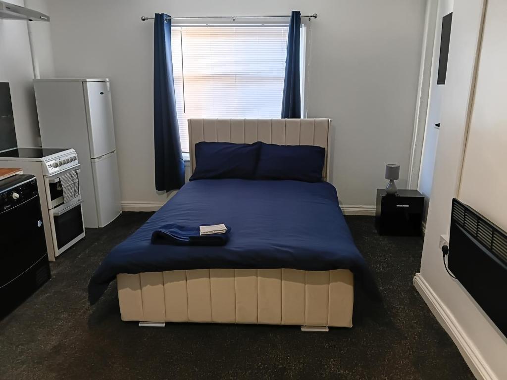 a bedroom with a large bed with a blue blanket at Studio Sleeps 2 with Parking in Oldbury