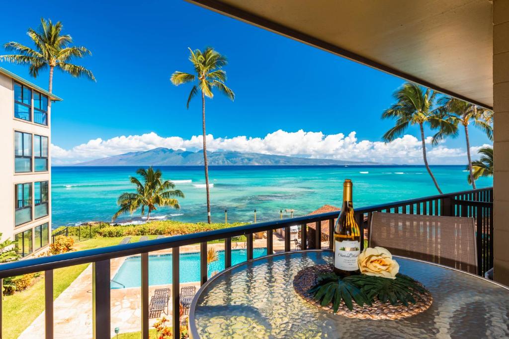 a table with a bottle of wine on a balcony overlooking the ocean at Noelani 212 in Kahana