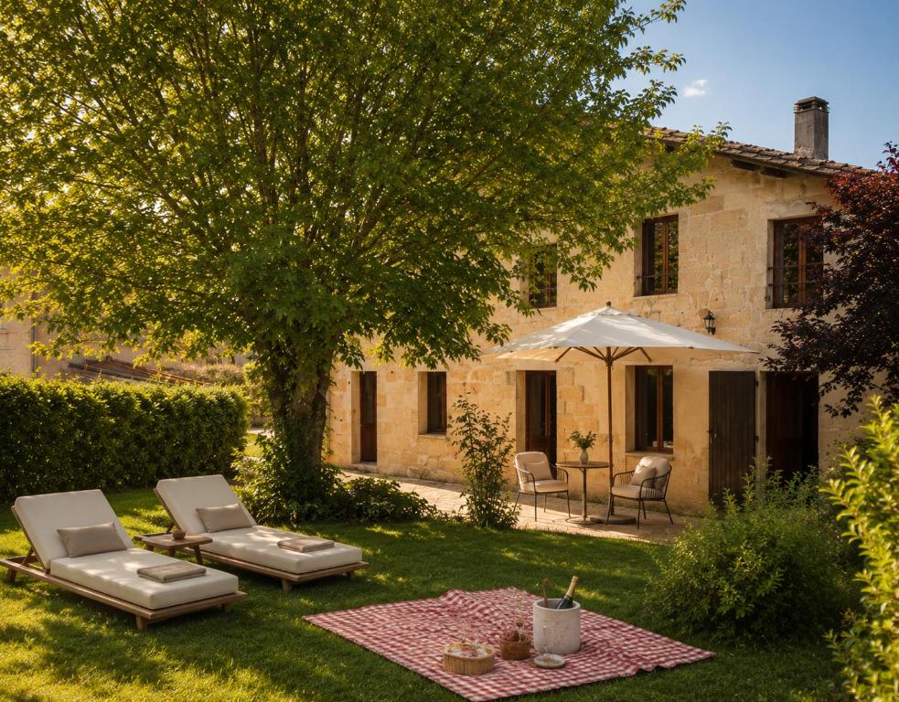 a garden with two lounge chairs and an umbrella at Maison Meraka - Design Guest House of Saint Emilion in Saint-Laurent-des-Combes
