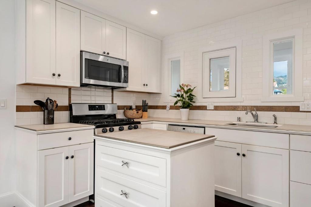 a white kitchen with white cabinets and a microwave at California Comfort in Santa Barbara