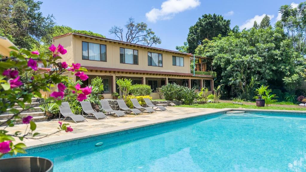 a house with a swimming pool and lounge chairs at Refugio del Colibrí in Tepoztlán