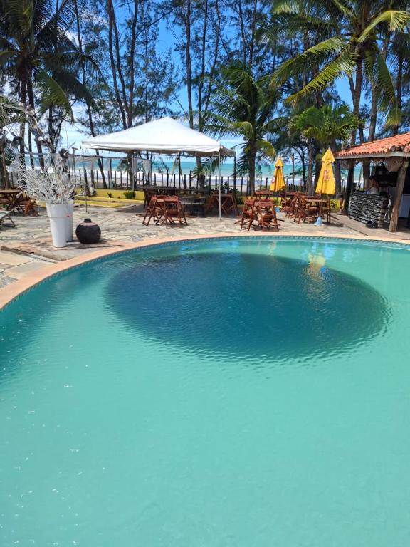 a large blue swimming pool next to a beach at Girassol praia hotel in Valença