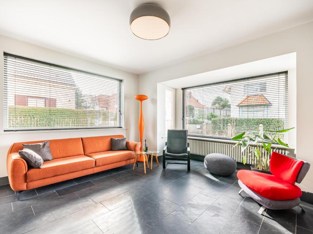 a living room with an orange couch and a red chair at La Terrasse in Sint-Idesbald