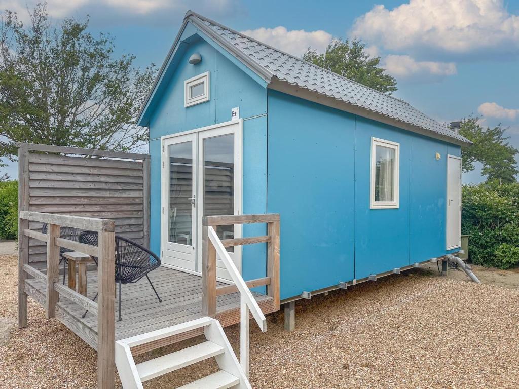 a blue tiny house with a chair on a deck at Bleubird in Ellemeet