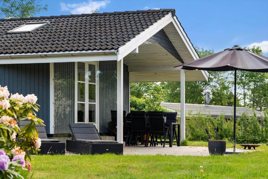 a screened in porch with an umbrella and chairs at fj1203-Jaegerspris-Birkagervej-14 in Jægerspris
