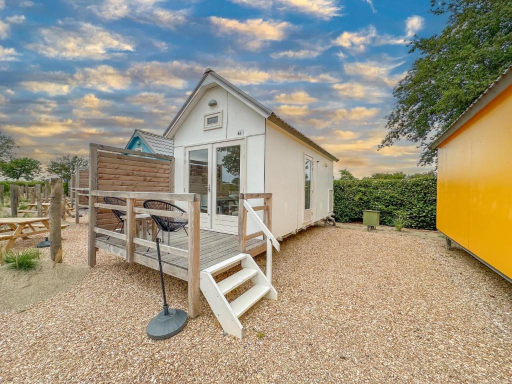 a tiny house with a porch and a swing at Surfers Cabin in Ellemeet