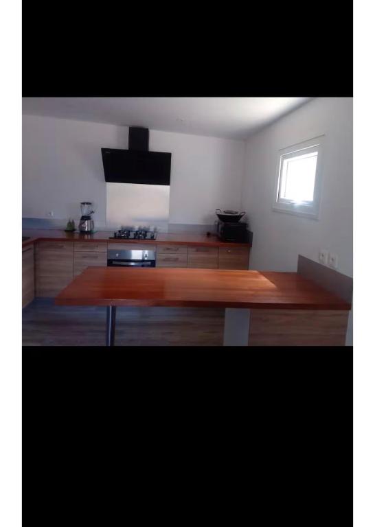 a kitchen with a wooden table in a room at Hafi in Païta