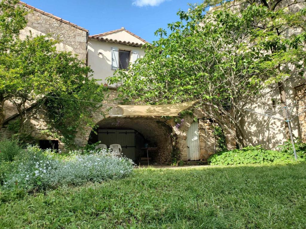 a stone building with a door in a yard at Aux Mimosas in La Tour-sur-Orb
