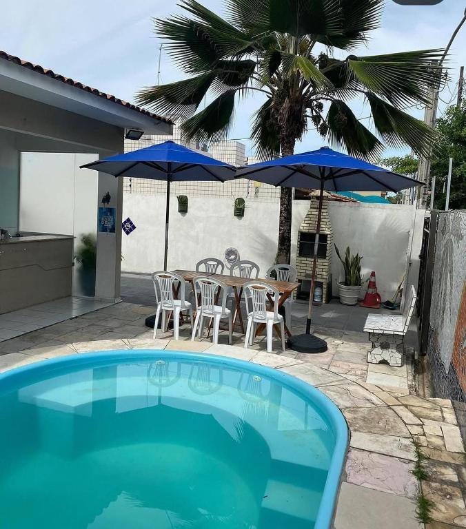 a swimming pool with umbrellas and a table and chairs at Pousada do Benzinho in Cabedelo