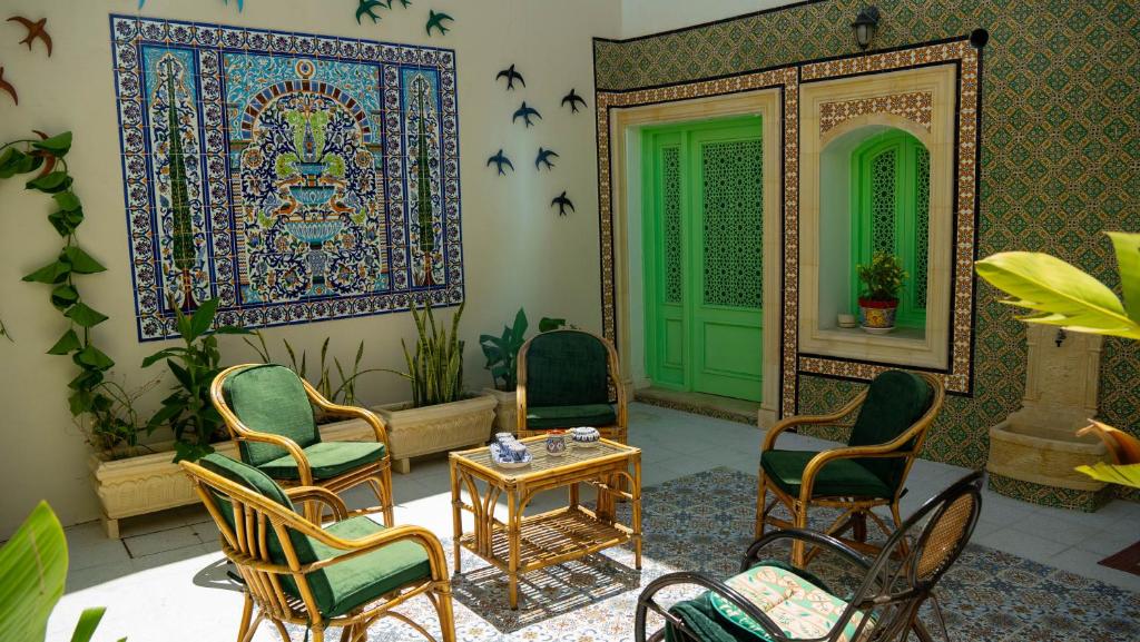 a room with chairs and a table and a green door at Maison Céline in Sousse