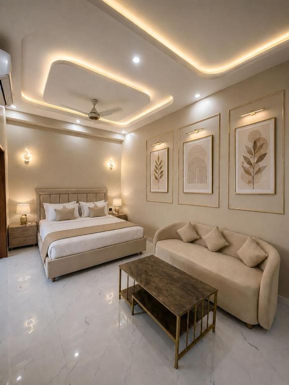a bedroom with a bed and a couch and a table at Hotel Regent DHA in Karachi