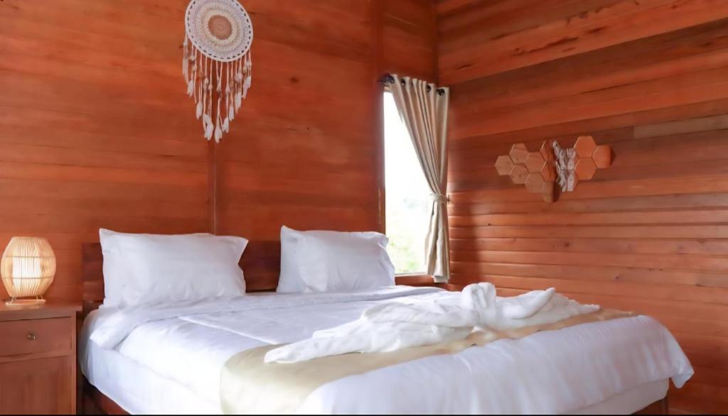 a bedroom with a bed with white sheets and a window at Nora Cottage Natural in Batununggul