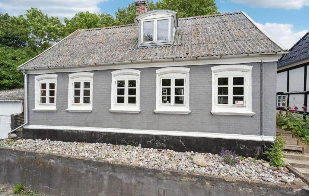a gray house with white windows on top of a wall at AE329-Aeroskobing-Oster-Bregninge-24 in Ærøskøbing