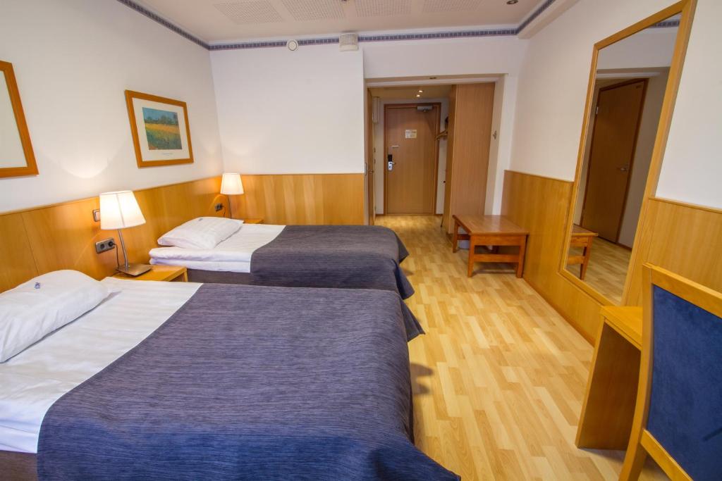 a hotel room with two beds and a mirror at Economy Hotel Savonia in Kuopio