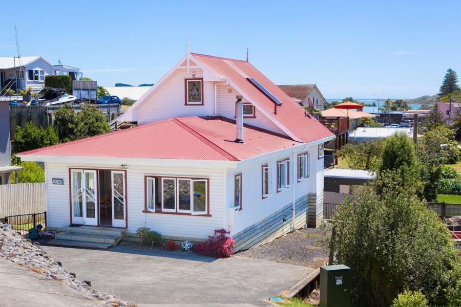 a small white house with a red roof at Large Bach in Raglan central in Raglan