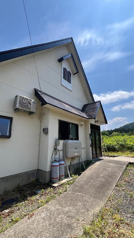 a white house with a window on the side of it at IWAKI Stay KAKUREGI in Hirosaki