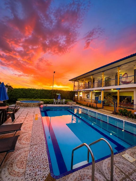 a pool in front of a building with a sunset at Finca Hotel Vista Palmar - Eje Cafetero in Quimbaya