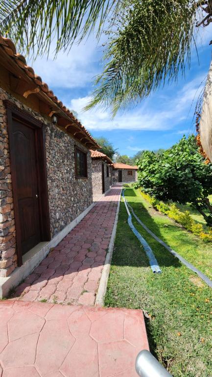 a house with a brick walkway next to a yard at Cabaña Oasis Ixmiquilpan in Ixmiquilpan