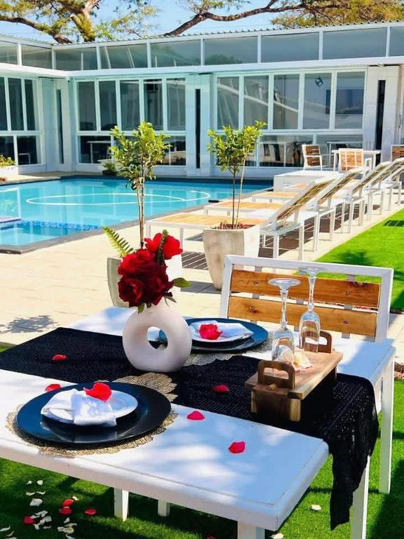 a white table with plates of food on it next to a pool at Lamamie Lodge in Thohoyandou