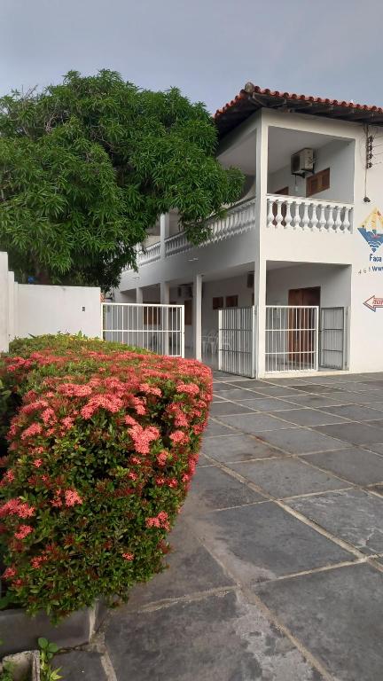 a building with a bush with red flowers in front of it at Hotel Amaro in Luis Correia