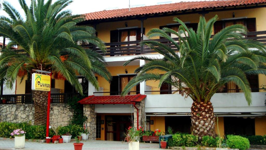 two palm trees in front of a building at Finikas Apartments in Polychrono