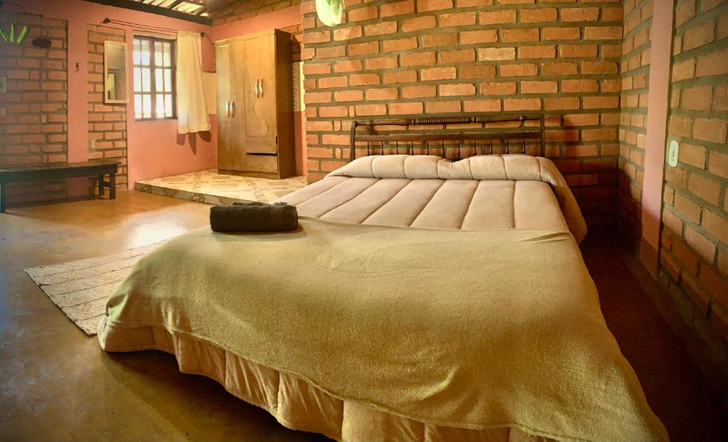 a large bed in a room with a brick wall at Kumaru Pousada e Restaurante in Palmeiras
