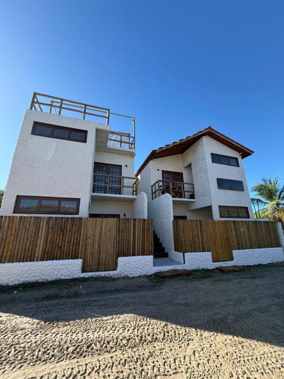 a house on the beach with a wooden fence at Villa Fênix Suítes in Barreirinhas